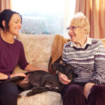 Live in care for younger people-old lady with dog and carer on the sofa