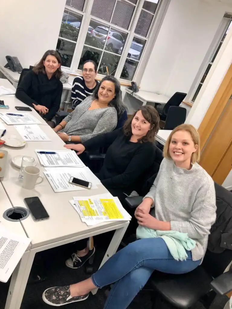 A group of five carers sat around a table completing their carer induction training.
