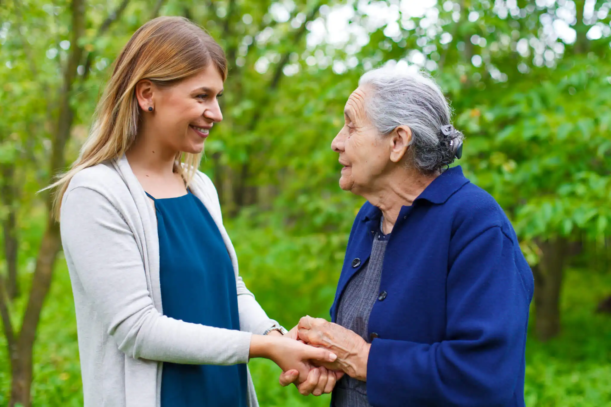 Older woman being supported by a professional carer on a walk in the countryside.