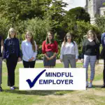 A photo of the Ashridge Home Care team standing outside with a mindful employer logo in the foreground.