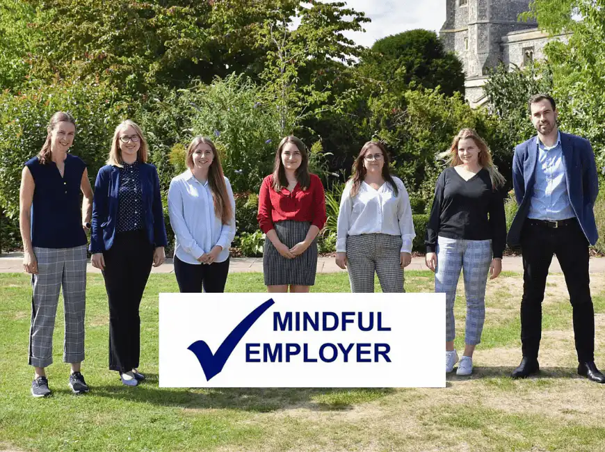 A photo of the Ashridge Home Care team standing outside with a mindful employer logo in the foreground.