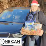 Trudi, owner and director of Ashridge Home Care delivering a food hamper for once can food bank and trust, whilst wearing a red Santa hat.