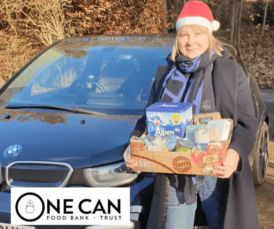 Trudi, owner and director of Ashridge Home Care delivering a food hamper for once can food bank and trust, whilst wearing a red Santa hat.