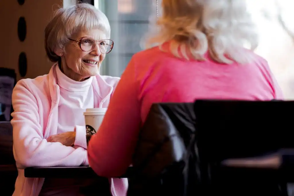 Two elderly ladies enjoying a catch up and a cup of coffee in a coffee shop.