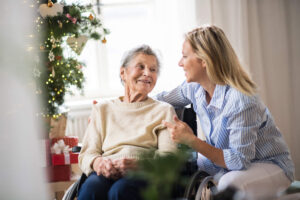 An elderly women and a relative together with a Christmas tree in the background.