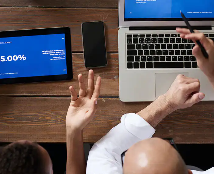 Two people sat at a table comparing survey results on a laptop and tablet.
