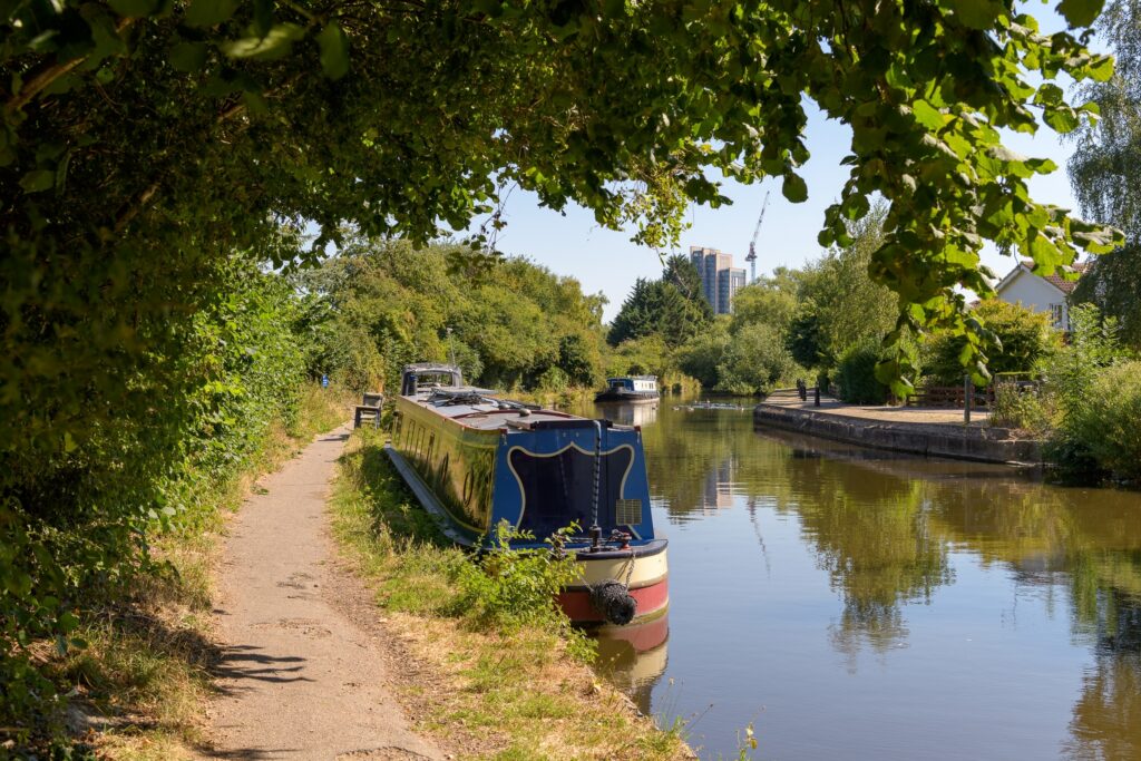 Canal boat on the Grand Union Canal with buildings of Watford, Hertfordshire in the background.