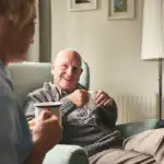 Man sitting enjoying a cup of tea with his professional carer