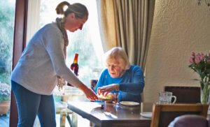 Carer serving old lady food and drink