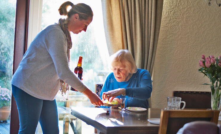 Carer serving old lady food and drink