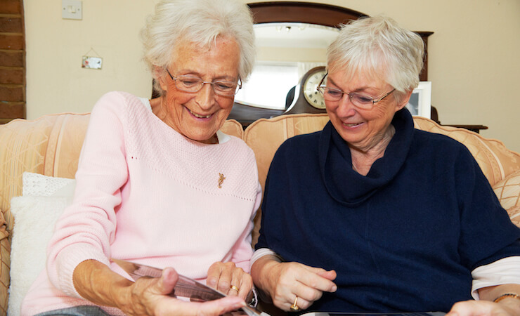 A carer and elderly woman browsing pictures